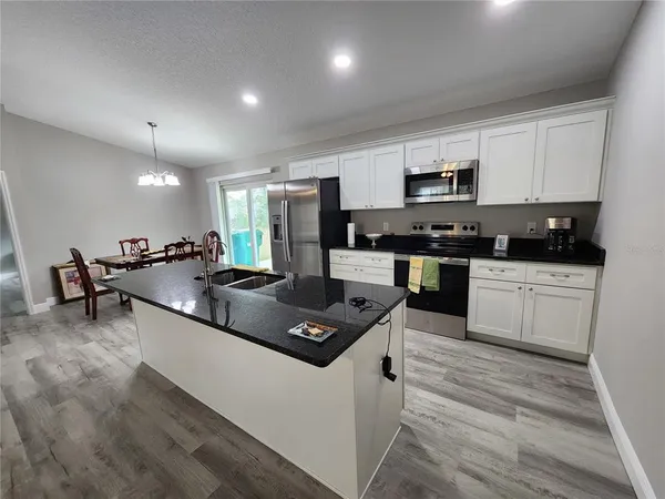 a kitchen with stainless steel appliances kitchen island granite countertop a stove a sink and a microwave