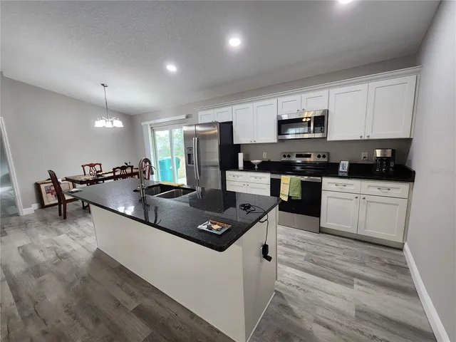 a kitchen with stainless steel appliances kitchen island granite countertop a stove a sink and a microwave