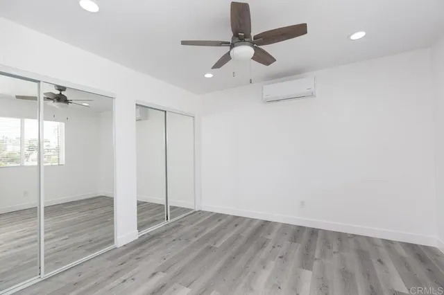 an empty room with wooden floor fan and windows