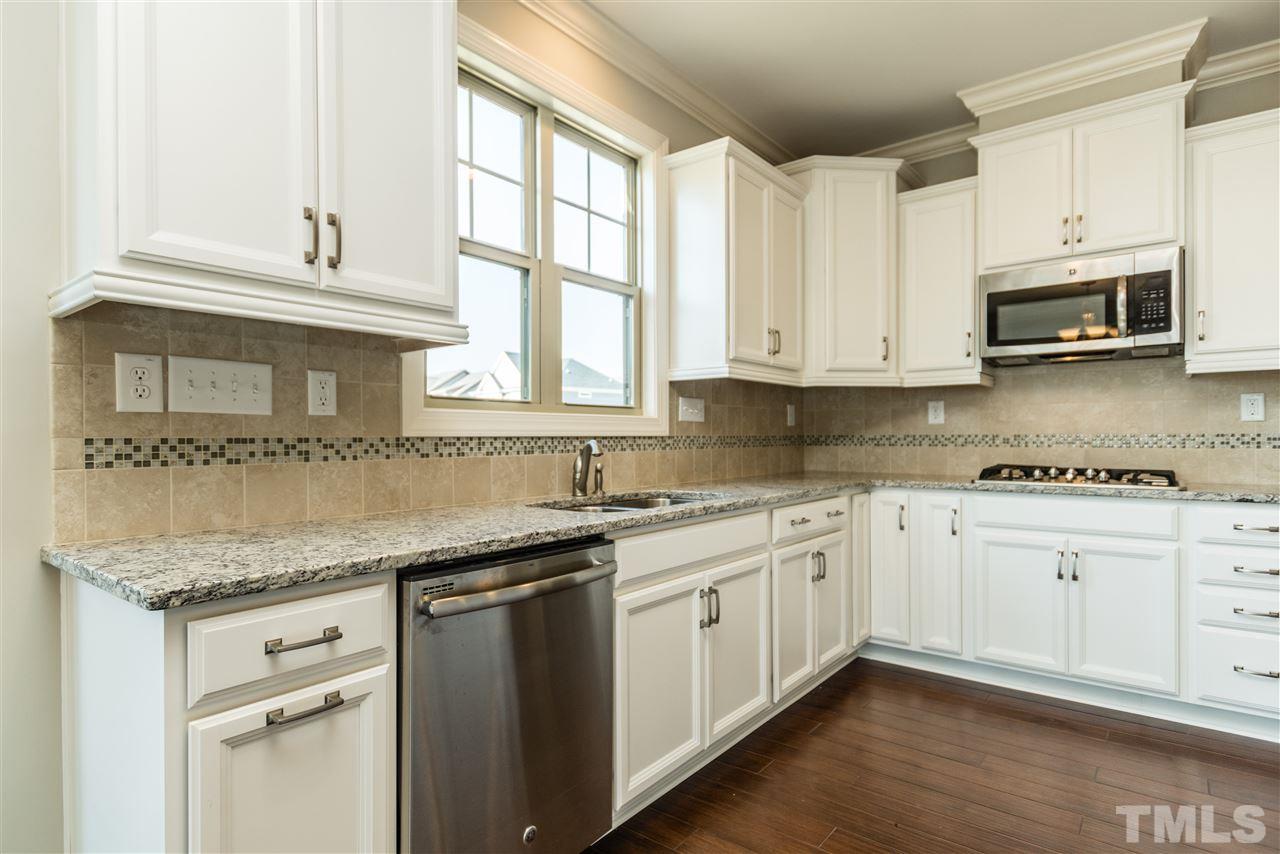 1505 Chestnut Falls Road Wendell, NC 27591 - Photo 8 of 25 Well appointed gourmet kitchen features include quiet stainless steel dishwasher, trash/compost pull out, soft close drawers, roll out treys in the base cabinets, undercabinet lighting, tile backsplash, window over the undermount kitchen sink and more...