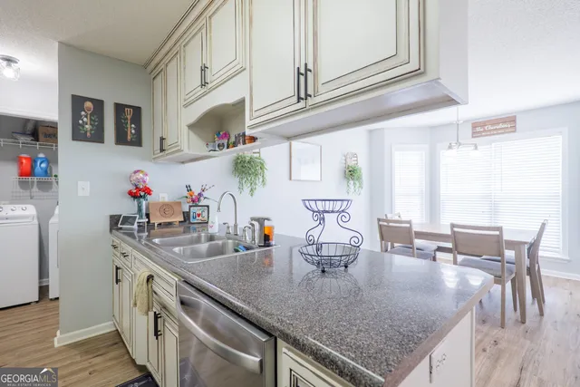 a kitchen with stainless steel appliances granite countertop a sink a stove and a wooden floors