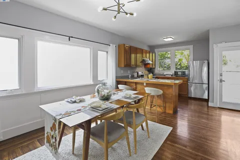 a kitchen with stainless steel appliances granite countertop a stove a refrigerator a sink a dining table and chairs with wooden floor