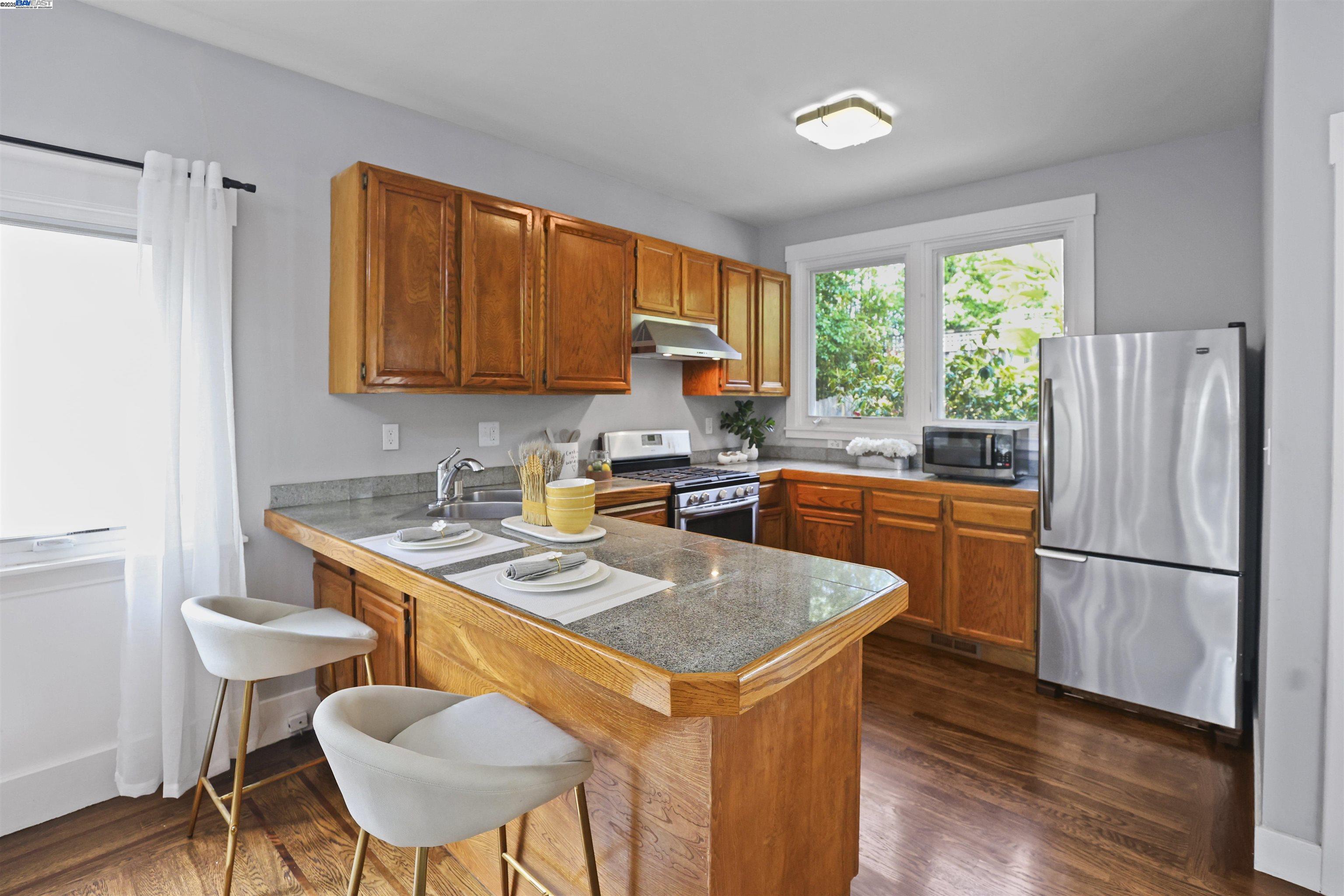 1361 Oakland Avenue Piedmont, CA 94611 - Photo 15 of 27 a kitchen with stainless steel appliances granite countertop a stove a refrigerator a sink a dining table and chairs with wooden floor