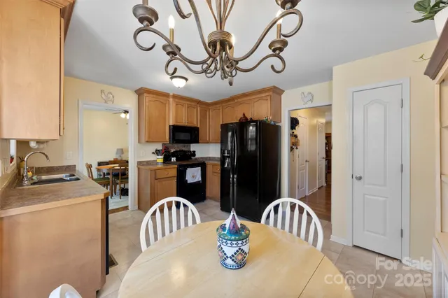 a kitchen with stainless steel appliances granite countertop a dining table chairs refrigerator and sink