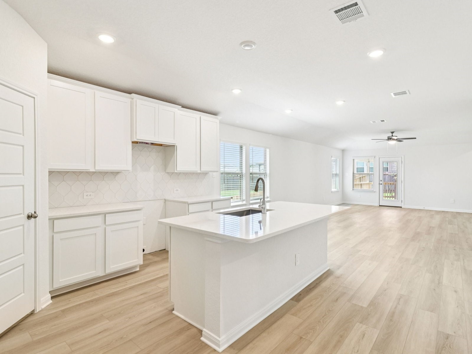 a large white kitchen with sink and cabinets