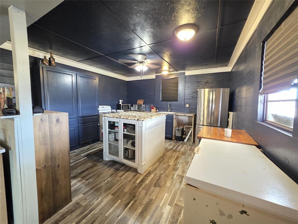 4451 Farm To Market 585 Bangs, TX 76823 - Photo 8 of 40 a kitchen with stainless steel appliances a stove a refrigerator a sink with wooden floor