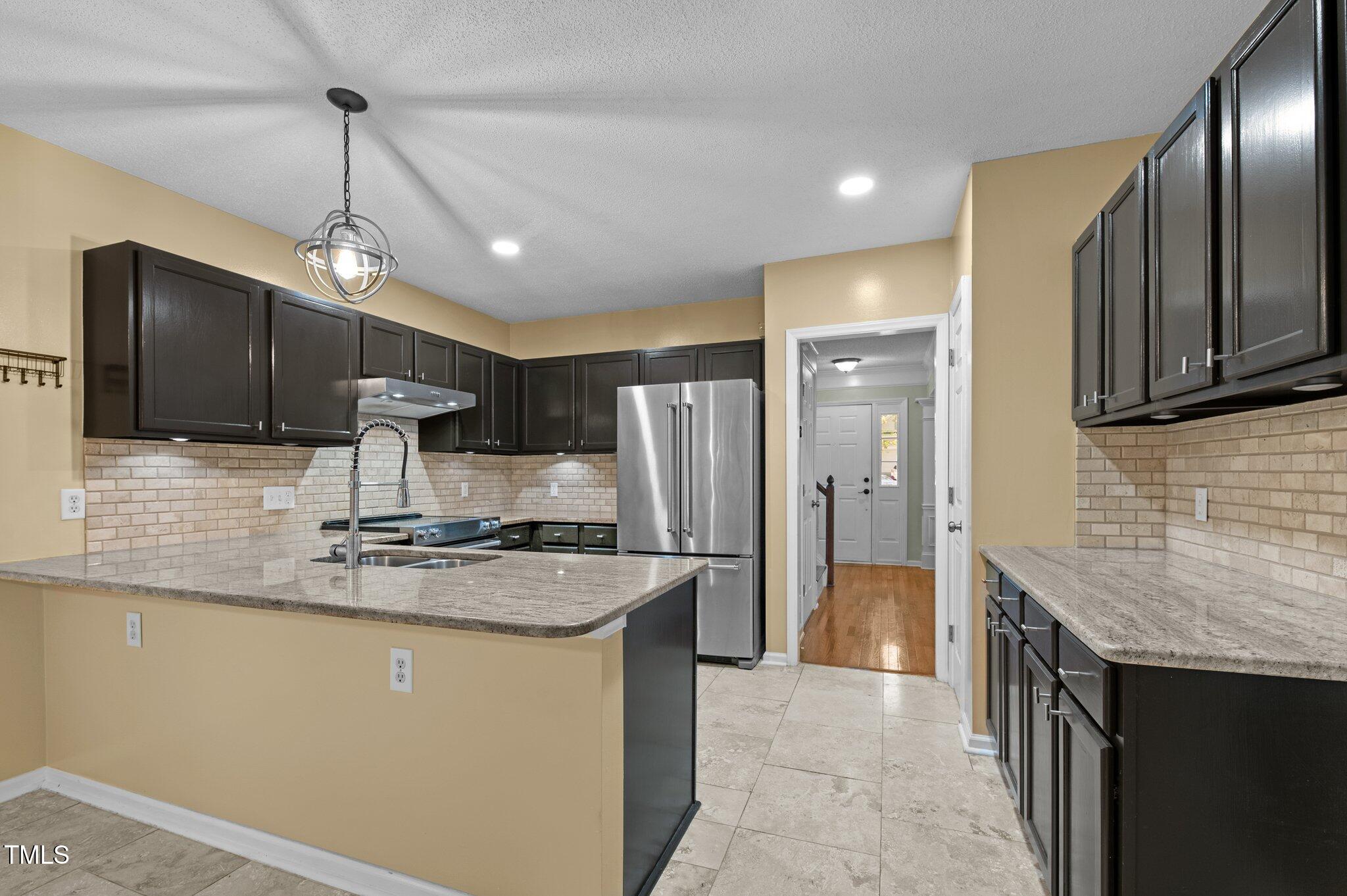 6209 Brielson Place Raleigh, NC 27616 - Photo 14 of 41 a kitchen with stainless steel appliances granite countertop a sink refrigerator and cabinets