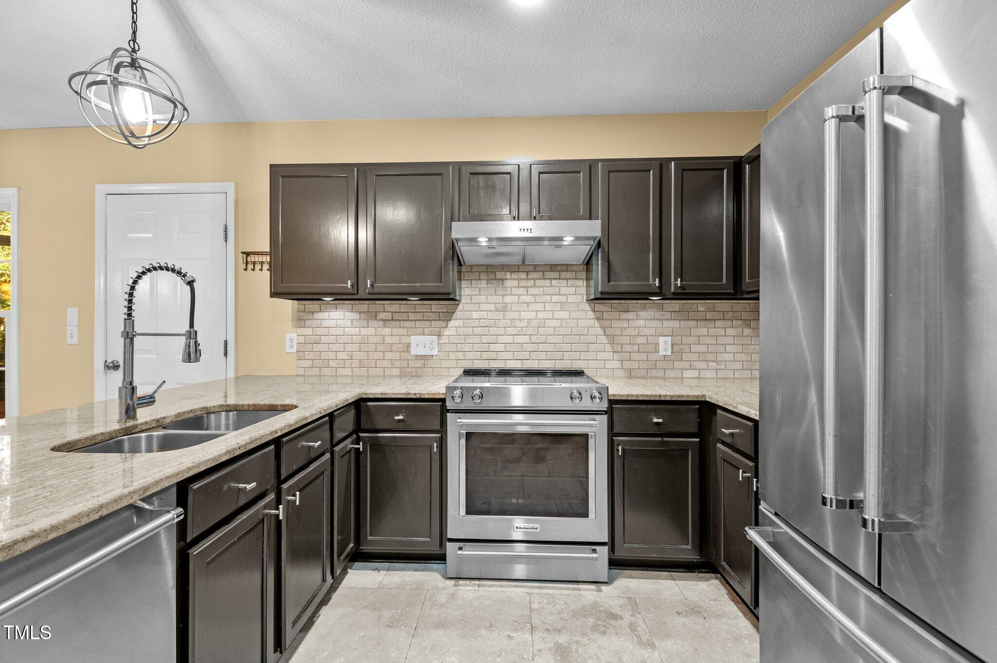 6209 Brielson Place Raleigh, NC 27616 - Photo 16 of 41 a kitchen with stainless steel appliances granite countertop a stove and a refrigerator