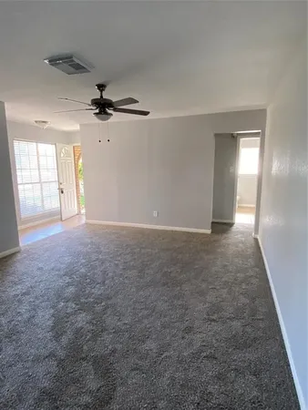 en empty room with windows and ceiling fan