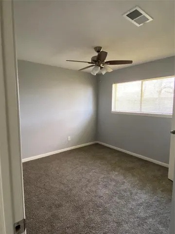an empty room with windows and fan