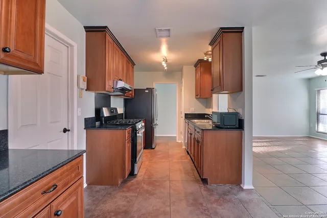 a kitchen with stainless steel appliances granite countertop a refrigerator a stove and a sink