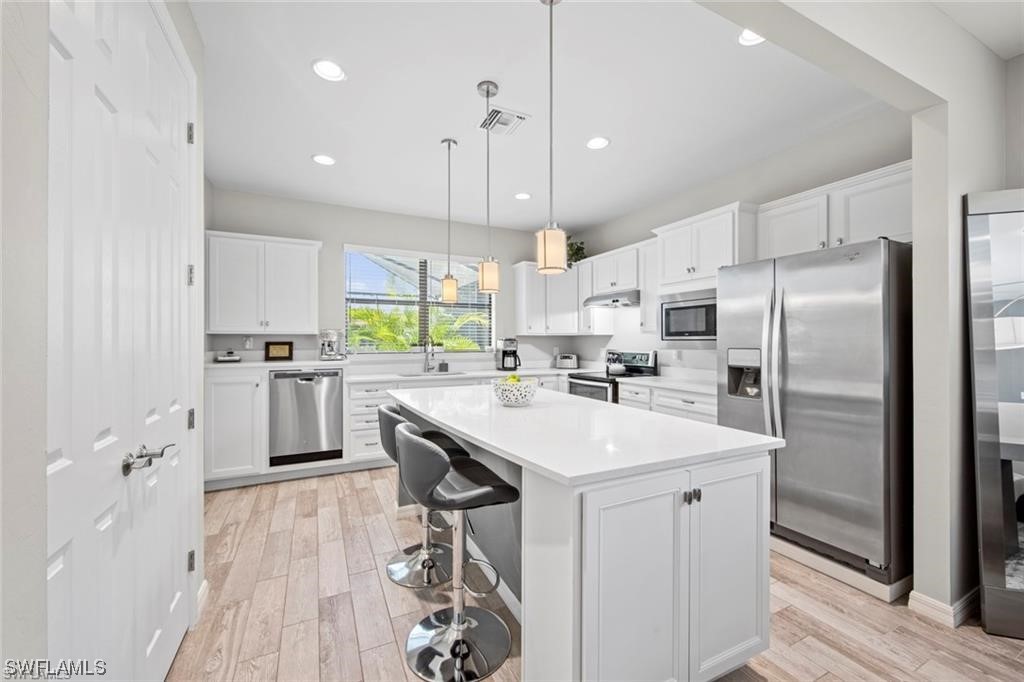 a kitchen with kitchen island a white cabinets and refrigerator