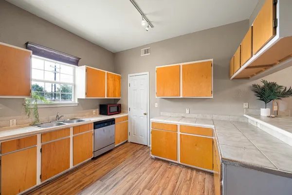 a kitchen with stainless steel appliances granite countertop a sink cabinets and wooden floor