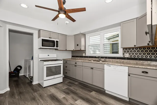 a kitchen with granite countertop a stove a sink and a microwave