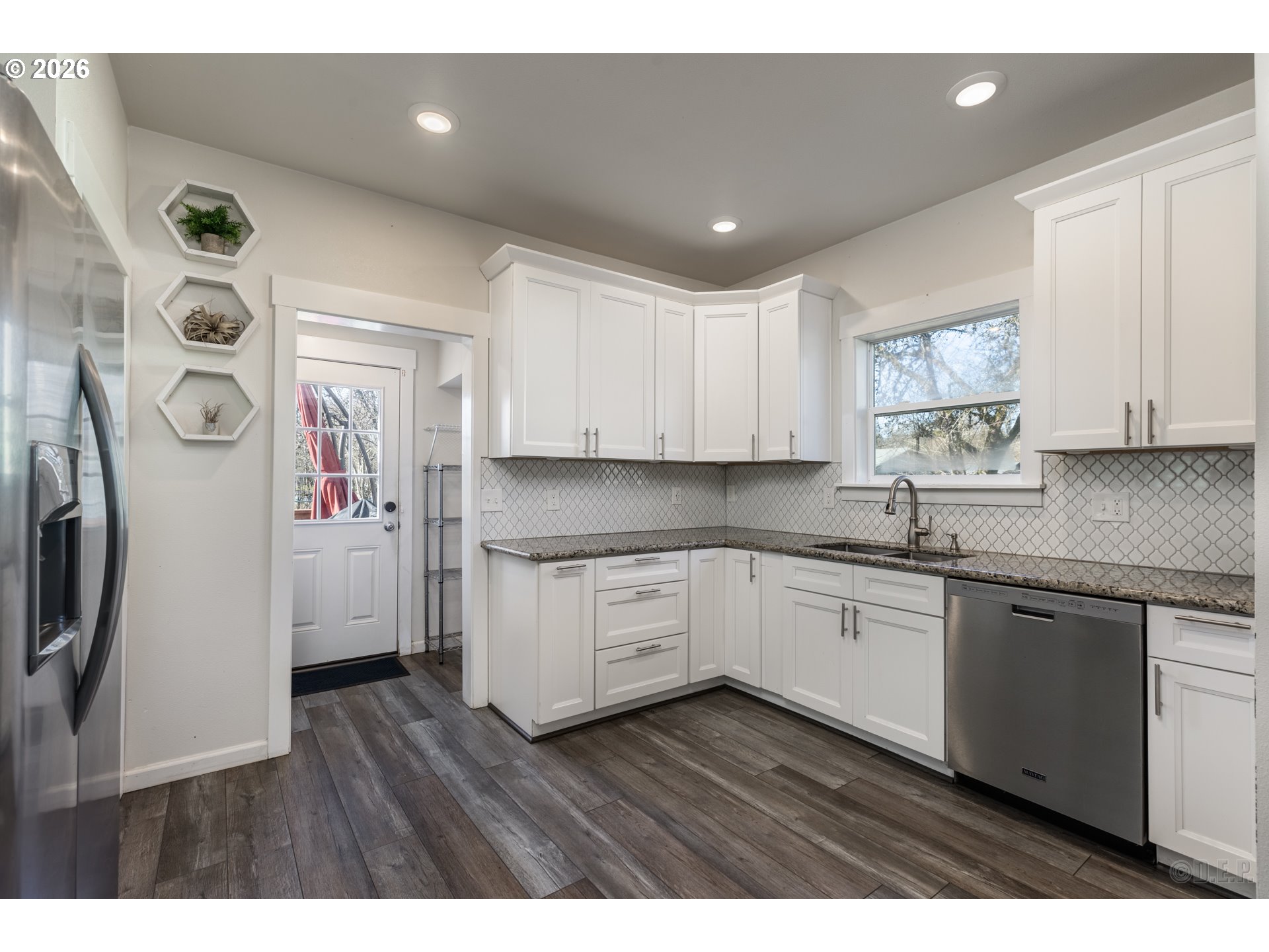 169 North Vernonia Road St. Helens, OR 97051 - Photo 8 of 27 a kitchen with stainless steel appliances granite countertop a refrigerator a sink dishwasher and white cabinets with wooden floor