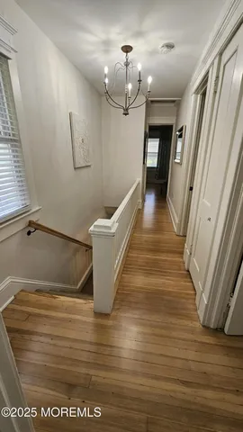 a view of a hallway with wooden floor and staircase