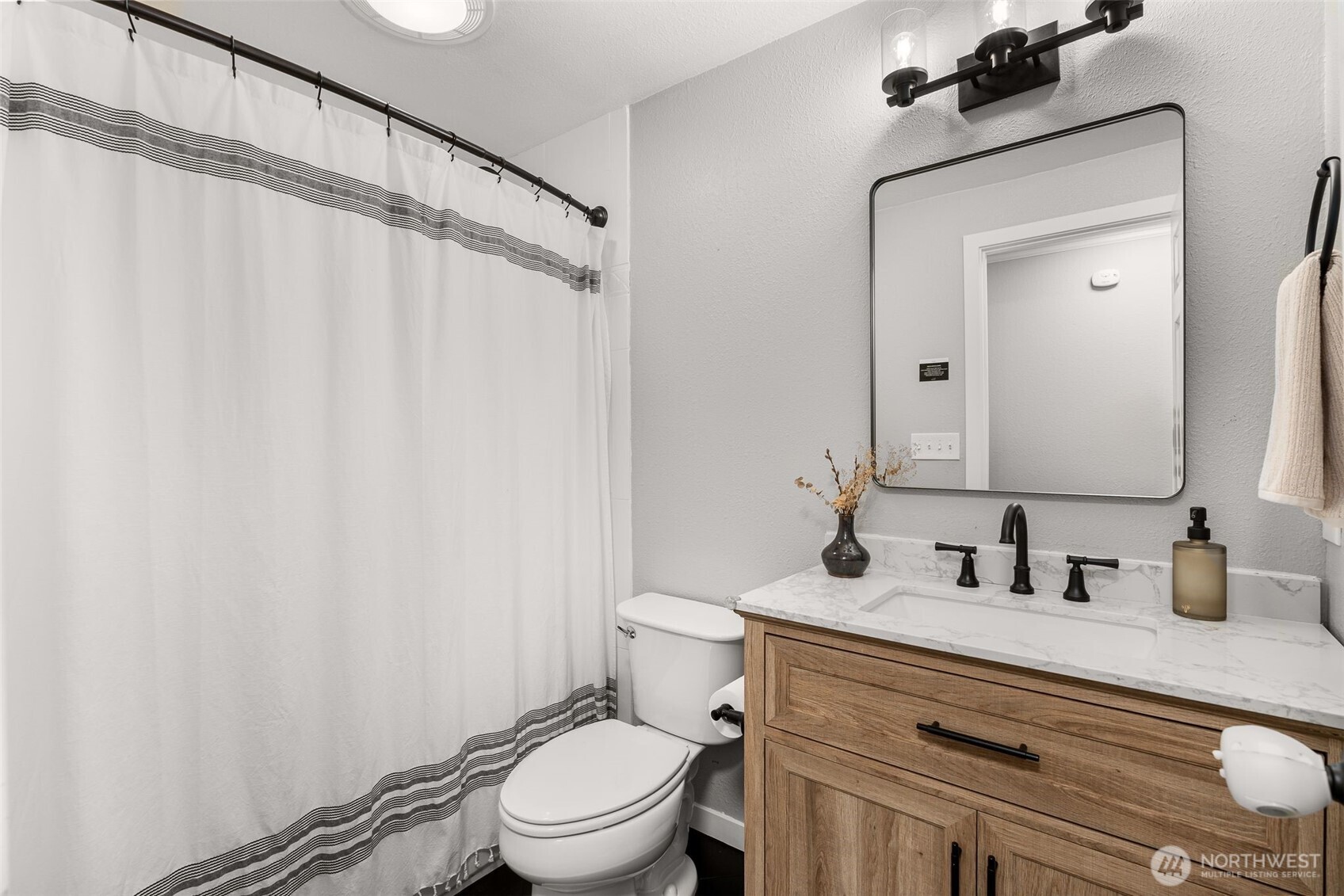 1128 203rd Place Southeast Bothell, WA 98012 - Photo 19 of 38 a bathroom with a sink a toilet a mirror and shower curtain