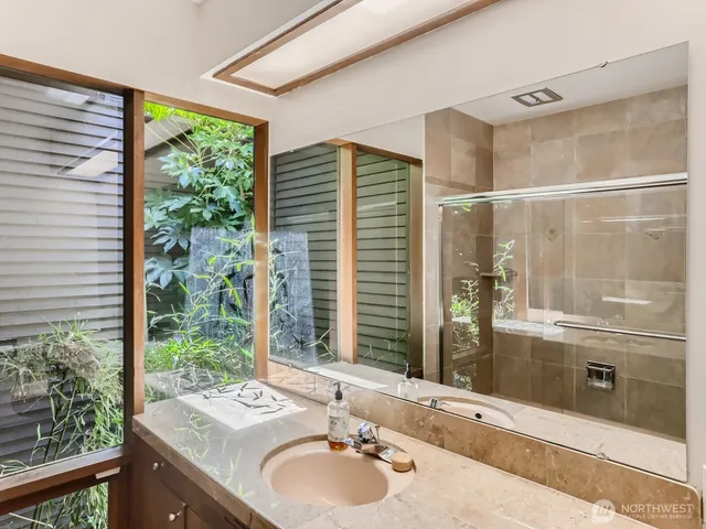 a bathroom with a granite countertop sink and a large window