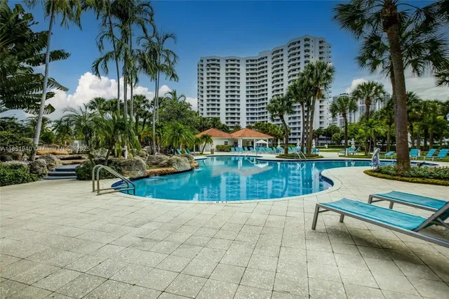 a view of swimming pool with a lounge chair and palm trees
