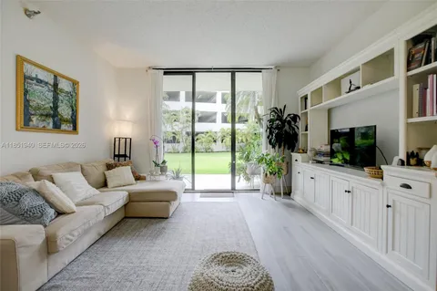 a living room with furniture large windows and wooden floor