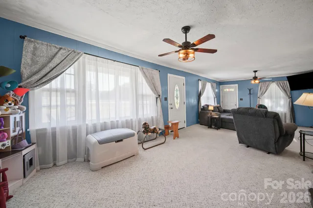 a living room with furniture a ceiling fan and a large window
