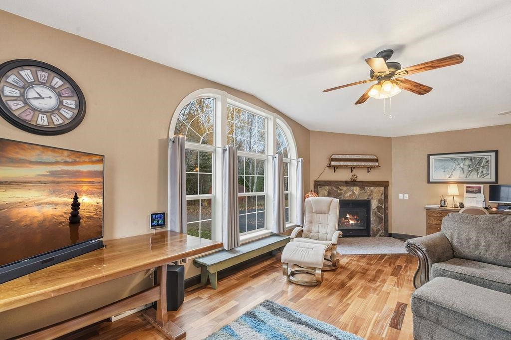 5251 Grabert Road Duluth, MN 55803 - Photo 16 of 50 Living area featuring wood finished floors, a warm lit fireplace, and a ceiling fan