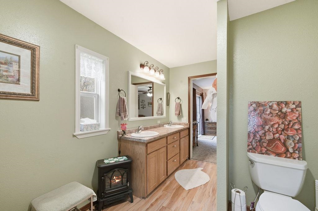 5251 Grabert Road Duluth, MN 55803 - Photo 22 of 50 Full bathroom featuring light wood-type flooring, double vanity, a textured wall, and a wood stove