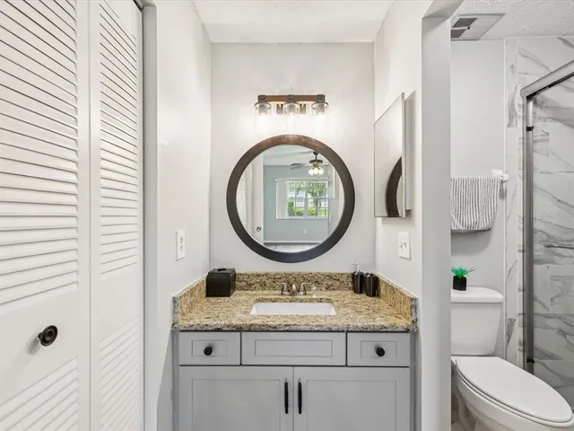 a bathroom with a granite countertop toilet sink and mirror