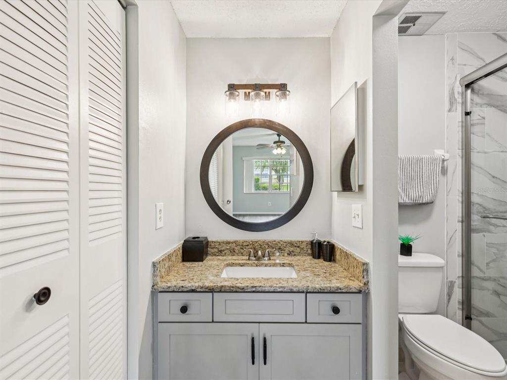3683 Trophy Boulevard, Unit 7 New Port Richey, FL 34655 - Photo 12 of 42 a bathroom with a granite countertop toilet sink and mirror