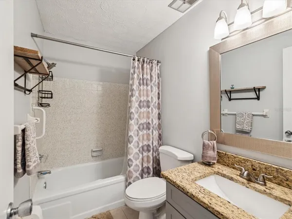 a bathroom with a granite countertop sink toilet a mirror and shower