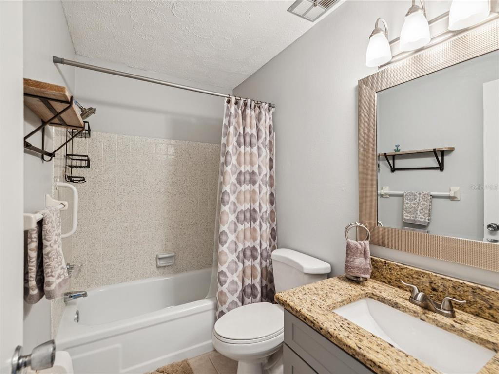 3683 Trophy Boulevard, Unit 7 New Port Richey, FL 34655 - Photo 16 of 42 a bathroom with a granite countertop sink toilet a mirror and shower
