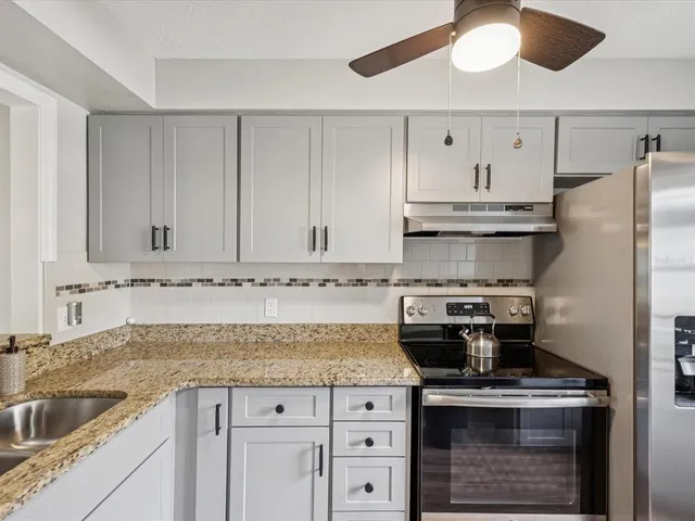 a kitchen with granite countertop a sink stainless steel appliances and cabinets