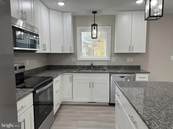 a kitchen with stainless steel appliances granite countertop a stove a refrigerator and a microwave