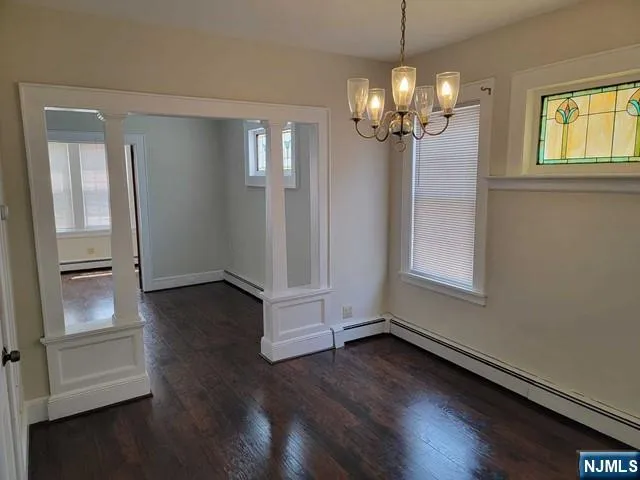 an empty room with wooden floor chandelier and windows