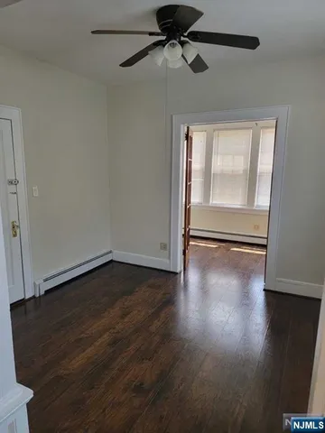 an empty room with wooden floor fan and windows
