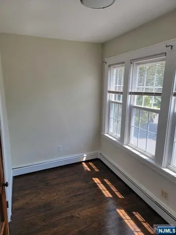 a view of an empty room and wooden floor and a window