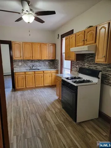 a kitchen with granite countertop wooden floors a stove and a sink