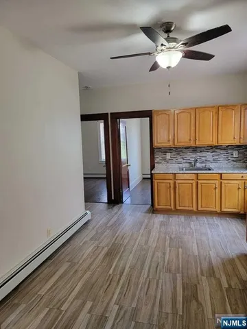 a view of a kitchen with a sink a ceiling fan and wooden floor