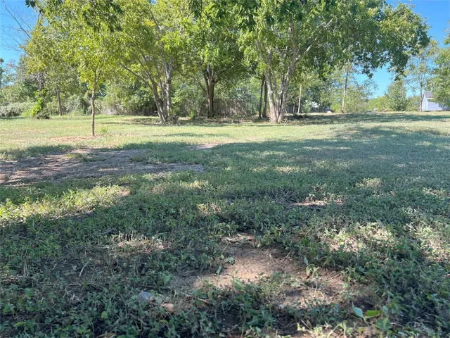 a big yard with lots of green space and trees all around