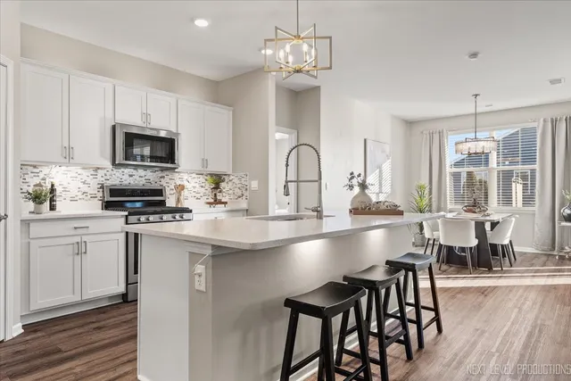 a kitchen with kitchen island granite countertop a table chairs microwave and refrigerator