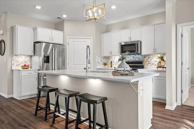 a kitchen that has a lot of white cabinets and stainless steel appliances
