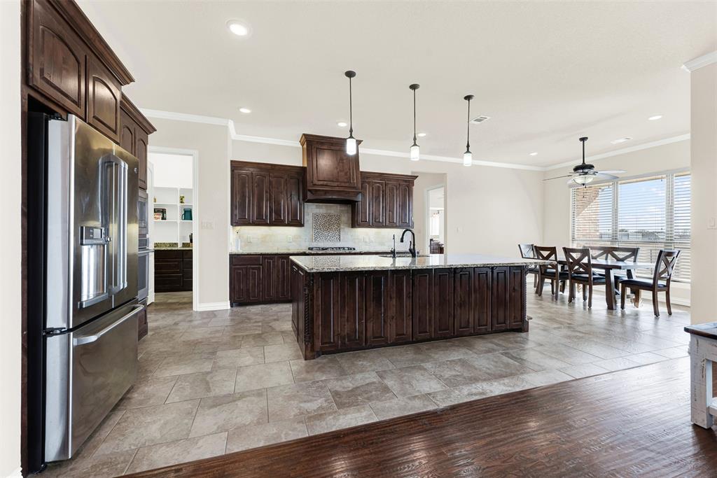 834 Audra Circle Rhome, TX 76078 - Photo 7 of 33 a kitchen with stainless steel appliances kitchen island granite countertop a table chairs refrigerator and sink
