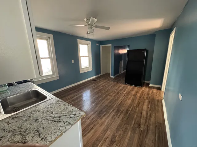 a view of a livingroom with wooden floor and kitchen space