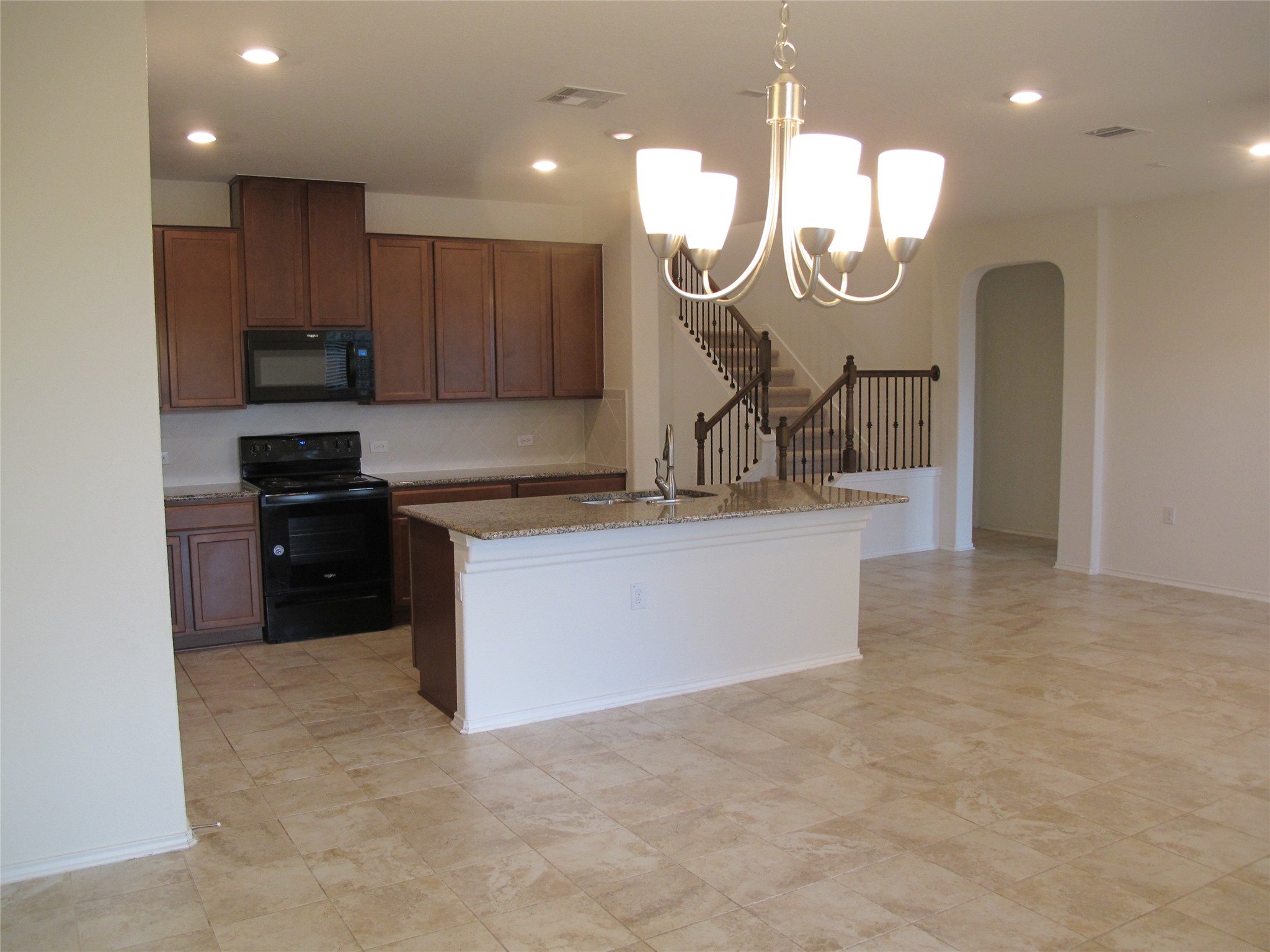 7820 Big Wind Way Austin, TX 78724 - Photo 15 of 37 Kitchen with black appliances, hanging light fixtures, a center island with sink, a chandelier, and recessed lighting