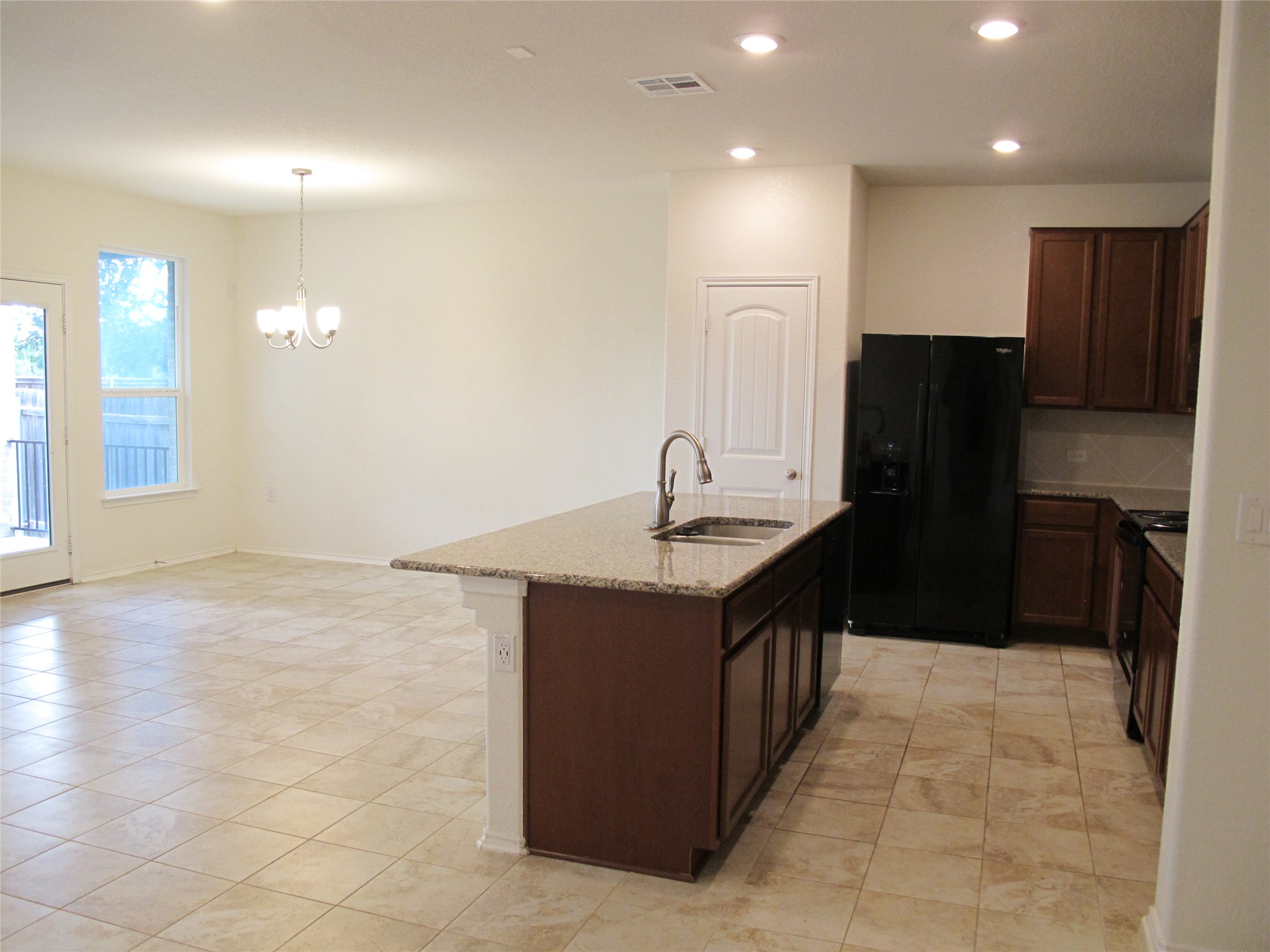 7820 Big Wind Way Austin, TX 78724 - Photo 16 of 37 Kitchen with black appliances, recessed lighting, dark brown cabinets, light stone countertops, and decorative light fixtures