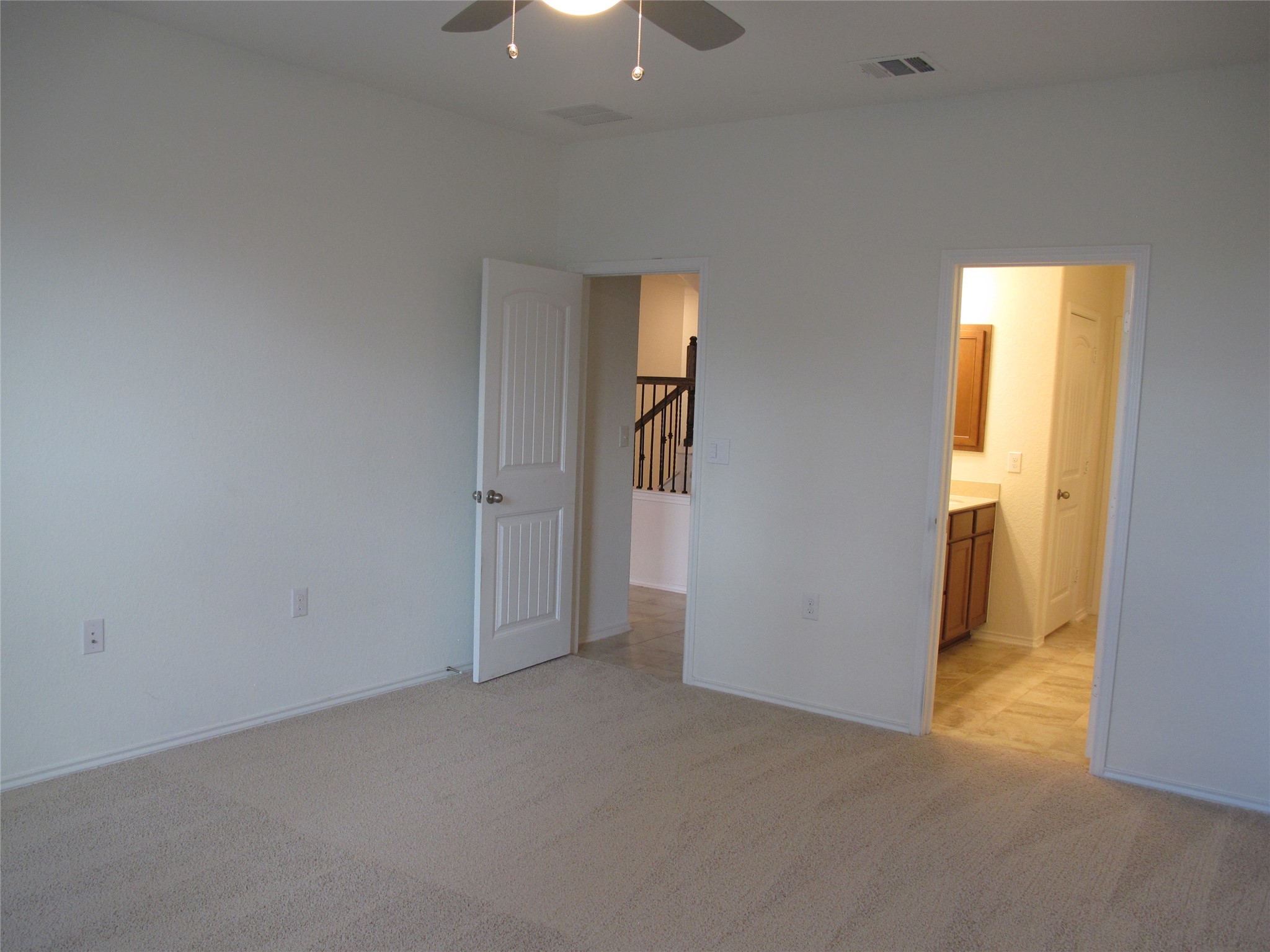 7820 Big Wind Way Austin, TX 78724 - Photo 21 of 37 Unfurnished bedroom with light carpet, a ceiling fan, and connected bathroom
