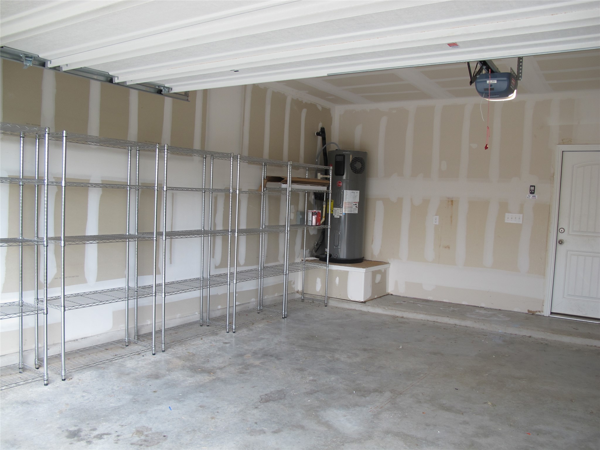 7820 Big Wind Way Austin, TX 78724 - Photo 35 of 37 Garage featuring water heater and a garage door opener