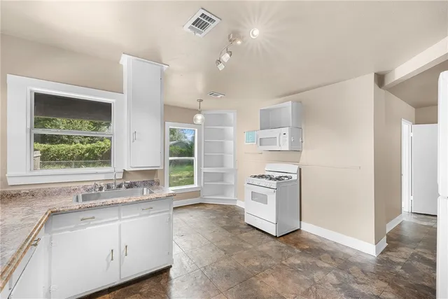 a kitchen with stainless steel appliances granite countertop a stove a sink and a refrigerator with wooden floor