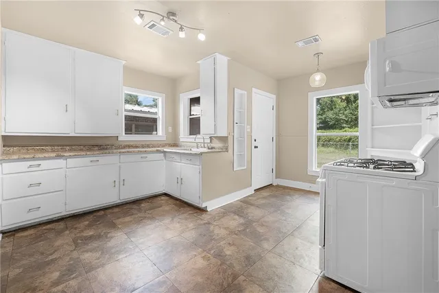 a kitchen with granite countertop a stove a sink cabinets and a refrigerator