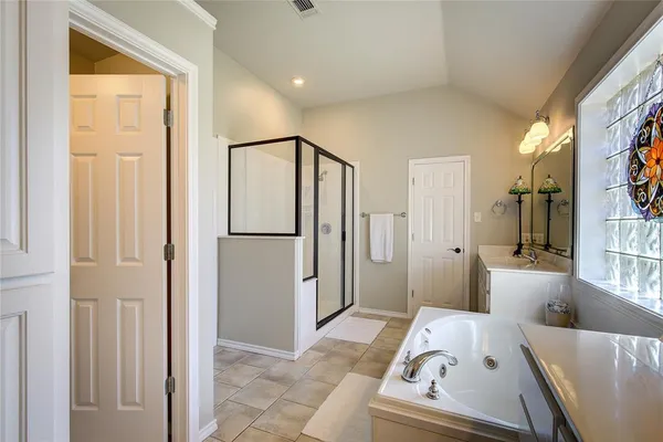 a walk in closet with wooden floor and a bathroom